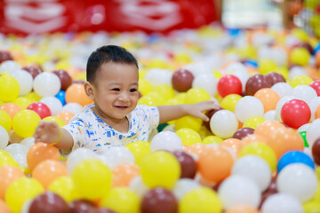 Asian cute baby is laughing and playing with toys feeling happy and cheerful on Indoor playground, Baby family concept.