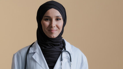 Portrait happy smiling muslim arab woman islamic doctor physician in hijab wear white medical coat looking at camera posing positive young female practitioner professional therapist standing indoors