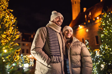 Fototapeta na wymiar winter holidays and people concept - happy smiling couple over christmas tree lights in evening city