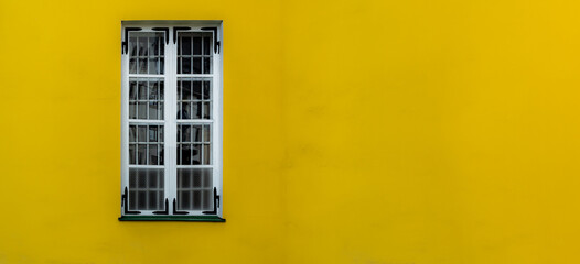 Fototapeta na wymiar Single window on a yellow wall with room for copy or text.