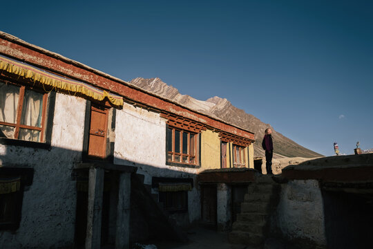 Woman traveler standing near Buddhist Tibetan monastery in Zanskar during sunset