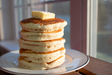 Five stacked homemade buttermilk pancakes with butter on top. 