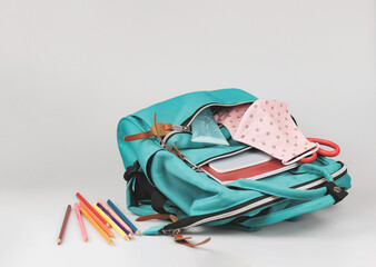back  to school  and new normal  concept.Front view of  pink polka dots fabric mask , sanitizer gel and  backpack with school supplies on white background.