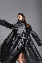 Naklejka premium young fashionable woman posing in black leather coat isolated on grey