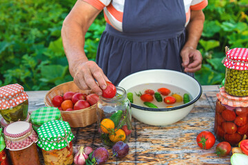 Senior woman preserving vegetables in jars. Selective focus.