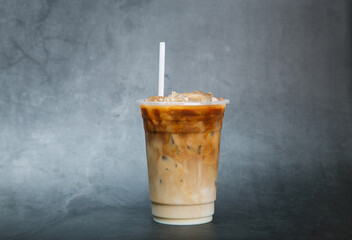 iced coffee in the plastic glass on black marble in studio background summer drink concept.
