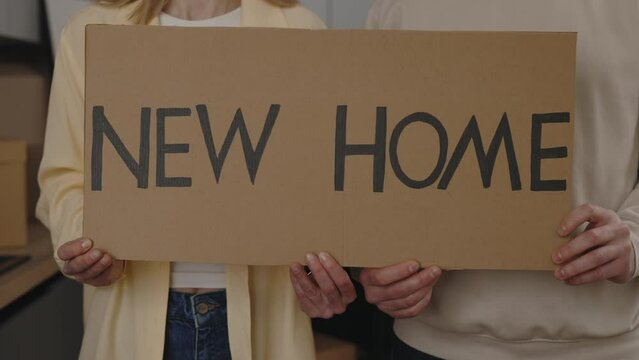 Close view of the couple hands holding the paper banner on the hew home background. New home and moving concept.