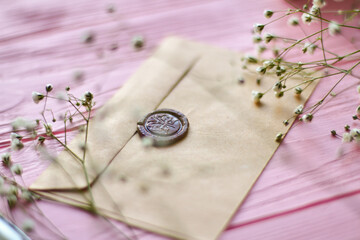 Close up envelope with brown wax seals. Pink wood background.