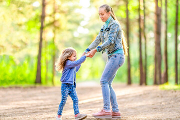 Mom and daughter are having fun in the forest. Summer sunny day. Playful mood