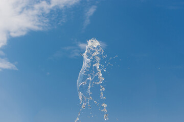 Naklejka na ściany i meble Clear water splash with droplet against blue sky with clouds