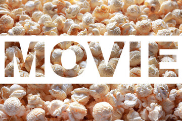 Popcorn texture background with inscription MOVIE. Word MOVIE on white background. Cinema poster concept.