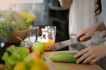 The close up of lady hand cutting cucumber to make their healthy food.