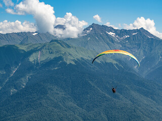 People in tandem paragliding at summer mountains background