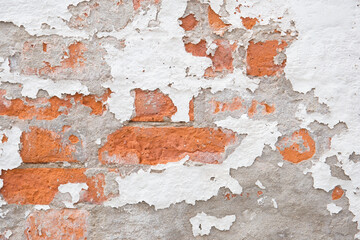 The shabby facade of an old brick building with damaged plaster.