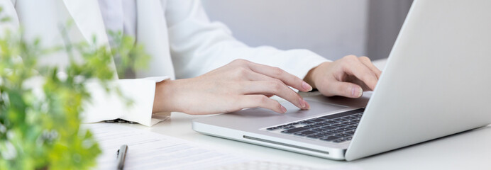 Fototapeta premium Businesswoman's hand presses on a laptop keyboard, World of technology and internet communication, Using computers to conduct financial transactions because the convenience and speed, Working concept.