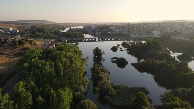 A view of drone river of calm water with medieval bridge at the foot of the old city of Alba de Tormes, Spain.