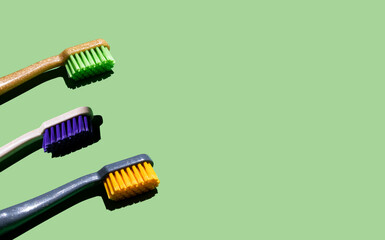 different toothbrushes on a light green background. Place for your text