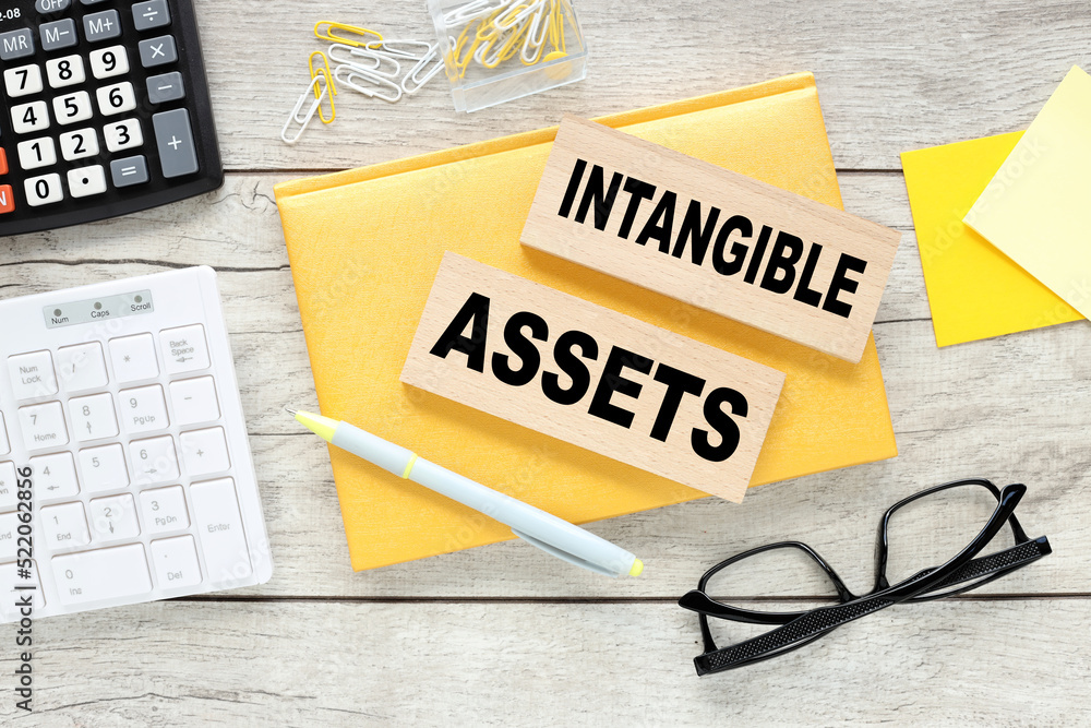 Aufkleber intangible assets text on wood block on yellow notepad