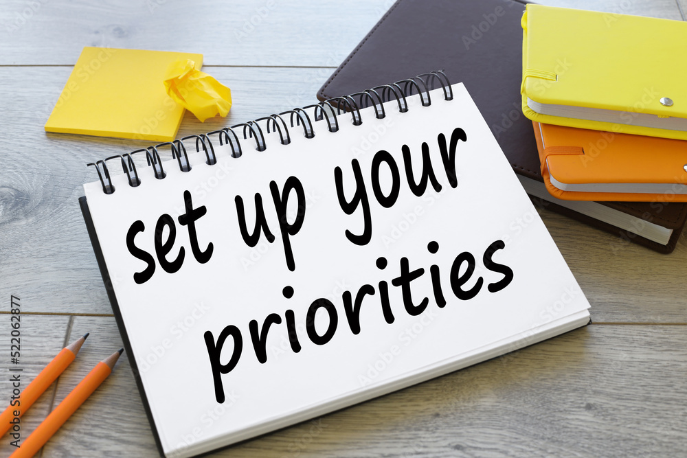 Poster set up your priorities text on notepad near pencils and orange notepad