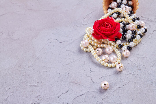 Pile of perals with red rose flower. Putty background with copy space.