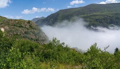 cloud rising up the valley below a large reservoir and dam in the mountains