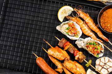 Various barbecue delicacies are placed on the black wood background