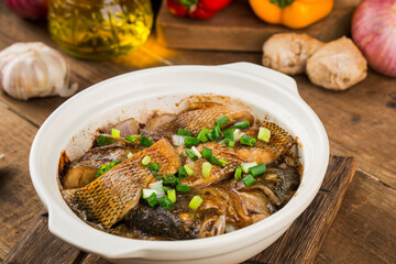 The delicious bass in casserole is placed on the wooden table