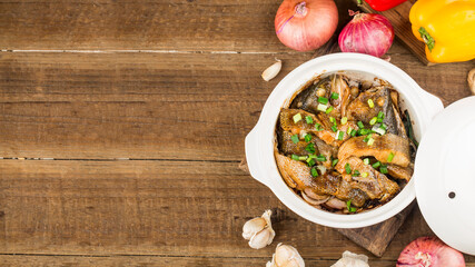 The delicious bass in casserole is placed on the wooden table