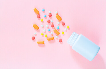 pills and pill bottles on pink background,White pills with selective focus and brown glass bottle on pink background. Antibiotic tablets of the epidemic on neutral backdrop with empty space for image 