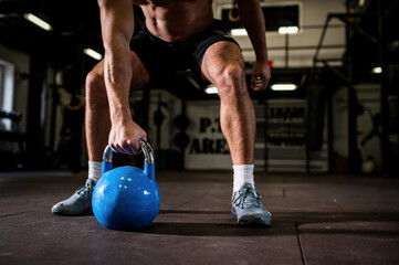 Fit young man in sportswear focused on lifting a dumbbell during an exercise class in a gym