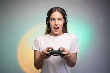 Game win. Happy female gamer in headphones rejoices in the victory in the game. Emotional gamer. Portable game console © Yuliia Sukharieva