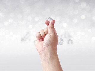Hand holding diamond ring on shining bokeh background