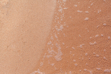 A soft wave runs on a sandy shore on a summer day. Empty space can be used as background for display or montage your top view products.