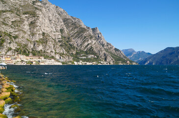 Fototapeta premium a beautiful old harbor in the Italian town of Limone sul Garda on turquoise lake Garda with mountains in the background (Lombardy)