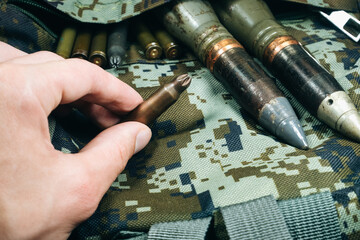 Soldier hold Bullets, shells, cartridges and projectiles on khaki camouflage backpack. Lend-Lease concept. Army concept. Sales of weapons and ammunition. Military industry, war, global arms trade.