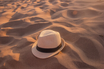 Fototapeta na wymiar Selective focus of straw hat isolated on a sandy background, straw hat on the dry sand, vacation concept