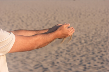 Sand flowing through man's hands in the sunset sunlight, white sand, holiday idea