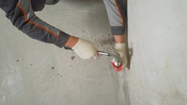Floor renovation concept. Cleaning the walls from excess hardened mortar after dismantling with a flat chisel and removing debris. 