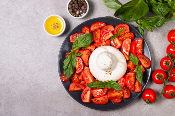 Traditional Italian burrata cheese with salad of delicious cherry tomato, basil leaves and olive oil.