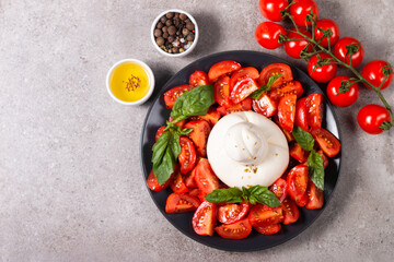 Traditional Italian burrata cheese with salad of delicious cherry tomato, basil leaves and olive oil.