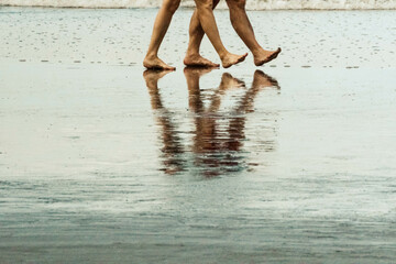 Fototapeta na wymiar legs of people walking on the beach
