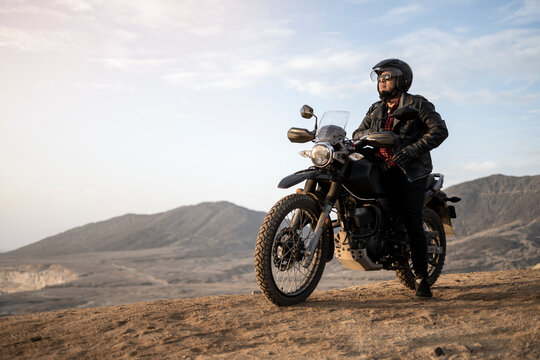 Latin man motorcyclist look the desert at sunset.