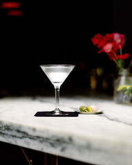 Ice cold martini sits on white marble bar