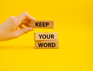 Keep your word symbol. Wooden blocks with words Keep your word. Beautiful yellow background. Businessman hand. Business and Keep your word concept. Copy space.