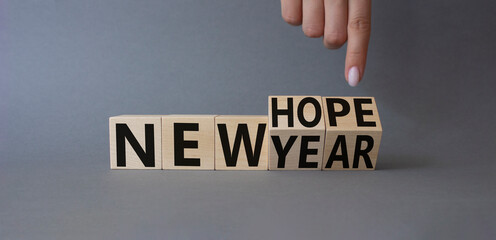 New year new hope symbol. Finger points at cubes with words new year and new hope. Beautiful grey background. Businessman hand. Business concept. Copy space