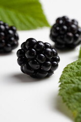 Three blackberries lie on the table on a white background. Selective focus. Macro.