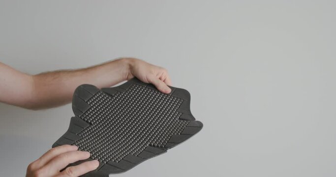 Moto back protection, inspection of an accessory for a moto jacket. Hands twist the plastic pad on the back.