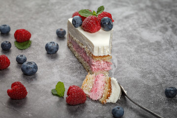 A piece of raspberry mint cake decorated with fresh raspberry and mint leaves