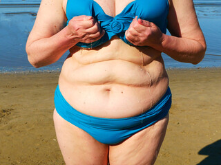 over size middle aged woman wearing in swimming suit squeeze your swimsuit out of the water, woman...