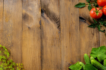 Wooden background. Fresh cucumbers, red tomatoes with leaves and dill on a wooden background. Place for text. copy space.